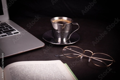 cup of coffee and laptop on black background