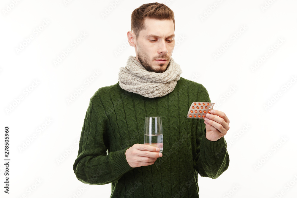 Man in a green sweater takes his prescribed meds.