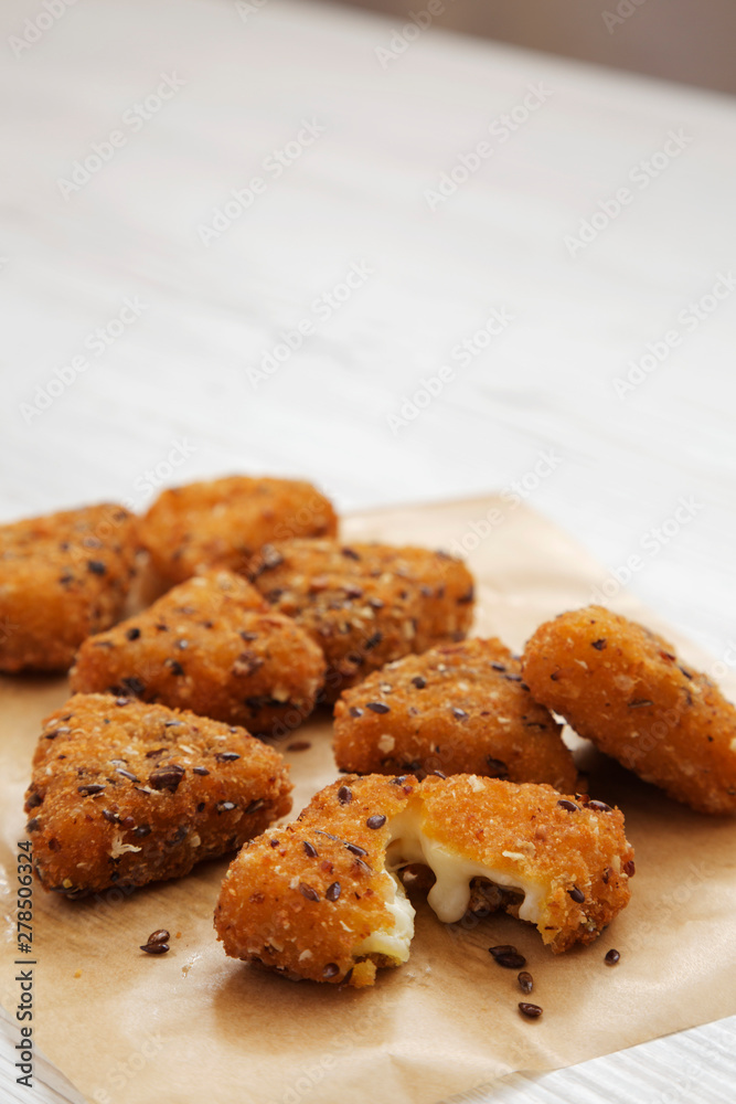 Fried camembert on a baking sheet on a white wooden surface, side view. Copy space. Fried camembert on a baking sheet on a white wooden surface, side view. Copy space.