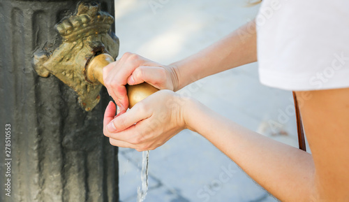 Canvas Print Girl is washing hands in the old medieval tap in the street