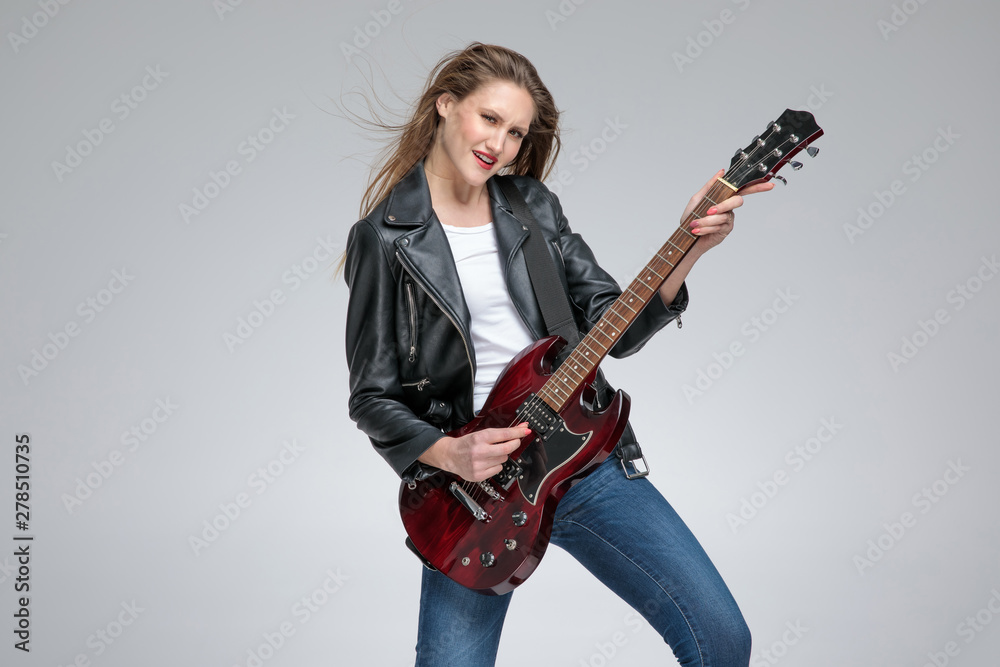 Passionate young girl playing guitar and wearing a leather jacket Passionate young girl playing guitar and wearing a leather jacket