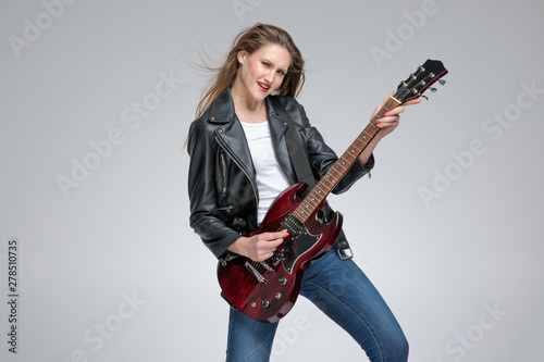 Passionate young girl playing guitar and wearing a leather jacket