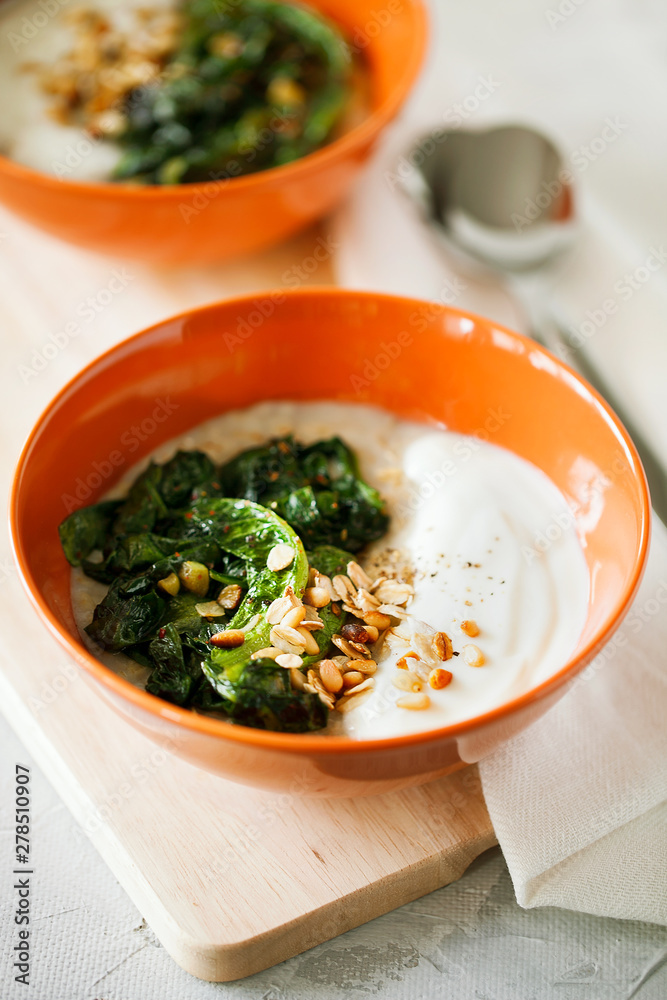 Healthy savory oatmeal with greens and Bulgarian yogurt high in fiber and protein in bowl on gray background,easy to prepare for breakfast or brunch.Healthy food,balanced diet concept Healthy savory oatmeal with greens and Bulgarian yogurt high in fiber and protein in bowl on gray background,easy to prepare for breakfast or brunch.Healthy food,balanced diet concept