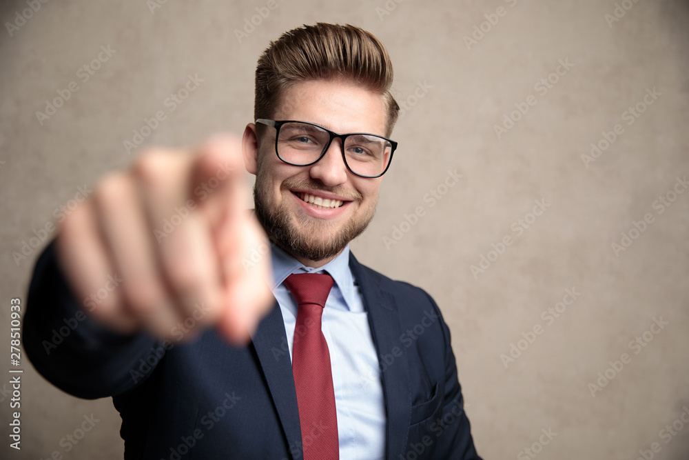 Positive businessman pointing and laughing while wearing a blue suit