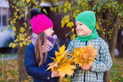 Smiling cute preteen kids collect maple leaves