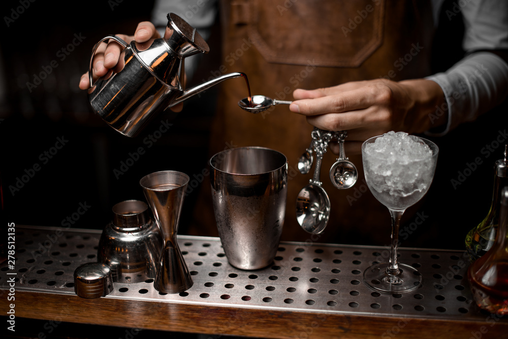 Bartender pouring an essence from the steel kettle to the spoon