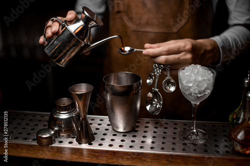 Bartender pouring an essence from the steel kettle to the spoon