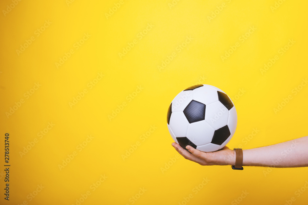 Photo of handsome arm, holding a  soccer ball, over yellow background