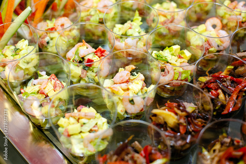 Catering at the event: disposable plastic cups with snacks - salads with shrimp, fresh and baked vegetables with sauce. Products included in the ketodiet. photo