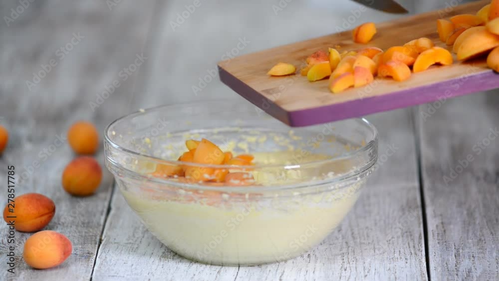Chef add apricots to cake batter. The hand mix apricots with batter. Making apricots cake.