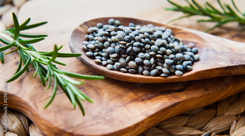 Green Puy lentils on wooden spoon.