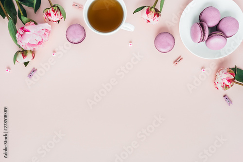 Top view of macaroons with a Cup of tea and peonies.
