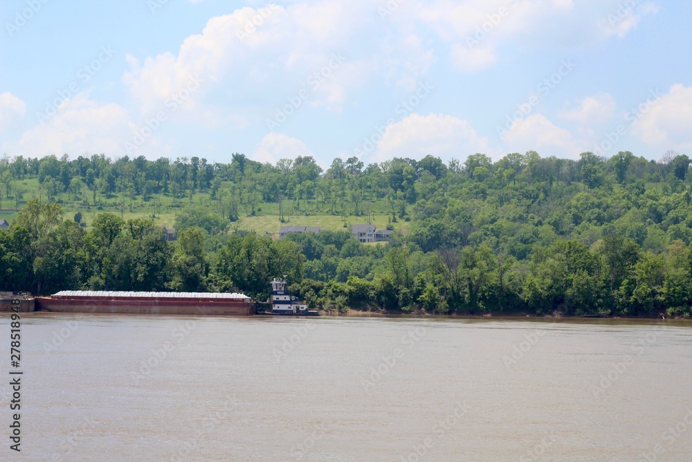 A barge parked on the shore of the river on a sunny day.