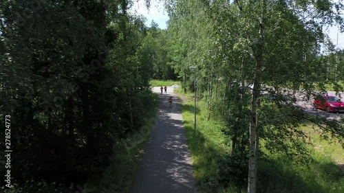 Drone footage of a group of athletes running down a paved path sided by trees. Filmed in realtime. photo