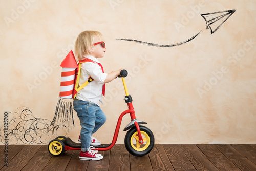 Happy child playing with toy rocket at home photo