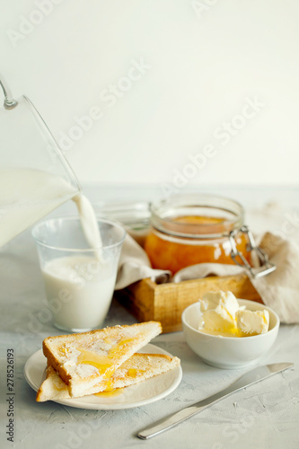 A stack of delicious toast with butter and glass of milk for Breakfast on the morning table.Healthy breakfast food concept.A stylish breakfast prepared on a light table close-up with space for text