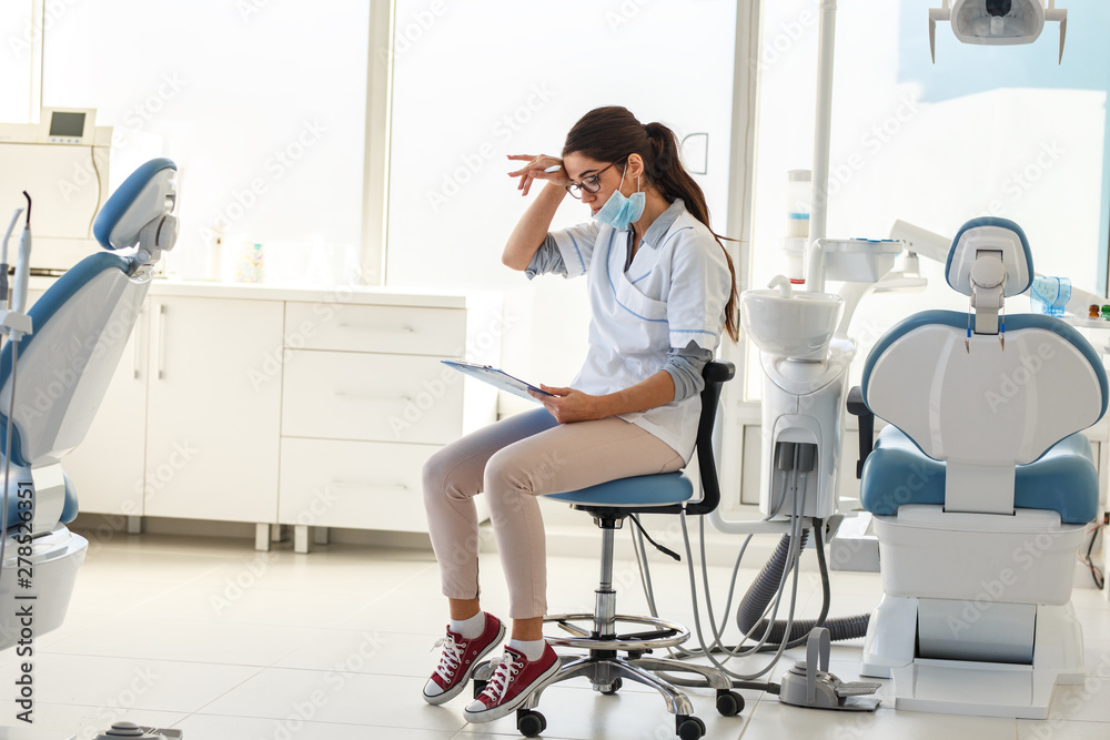 Female dentist in dental office .She tired after hard work, sitting on ...