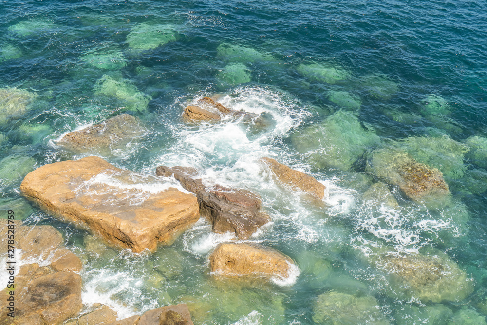 Ocean coast. Calm waves crash against stones on a quiet sunny day.