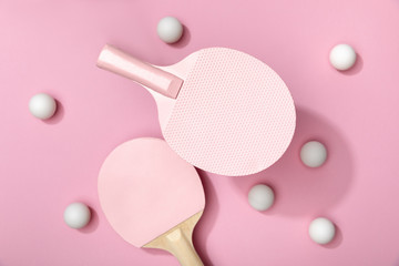 top view of white table tennis balls and rackets on pink background