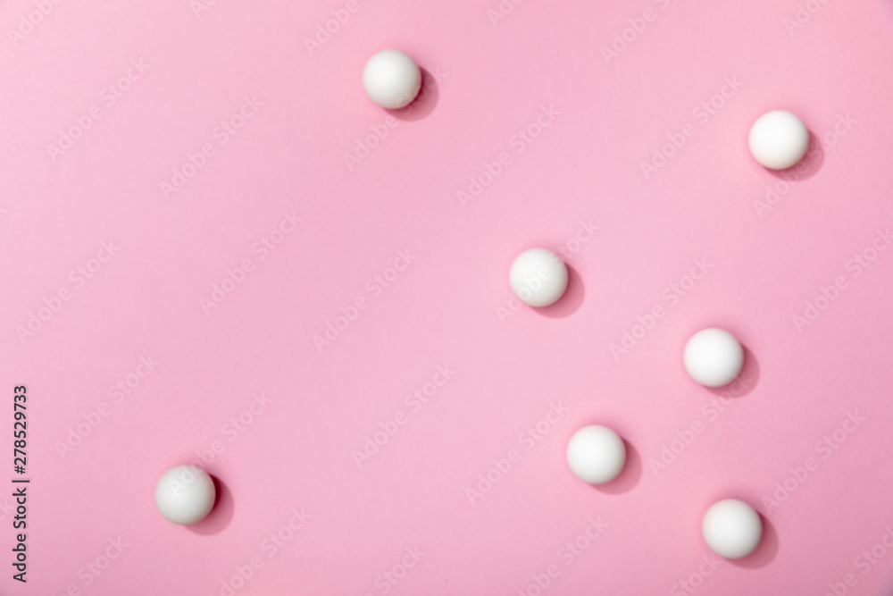 top view of white table tennis balls scattered on pink background top view of white table tennis balls scattered on pink background