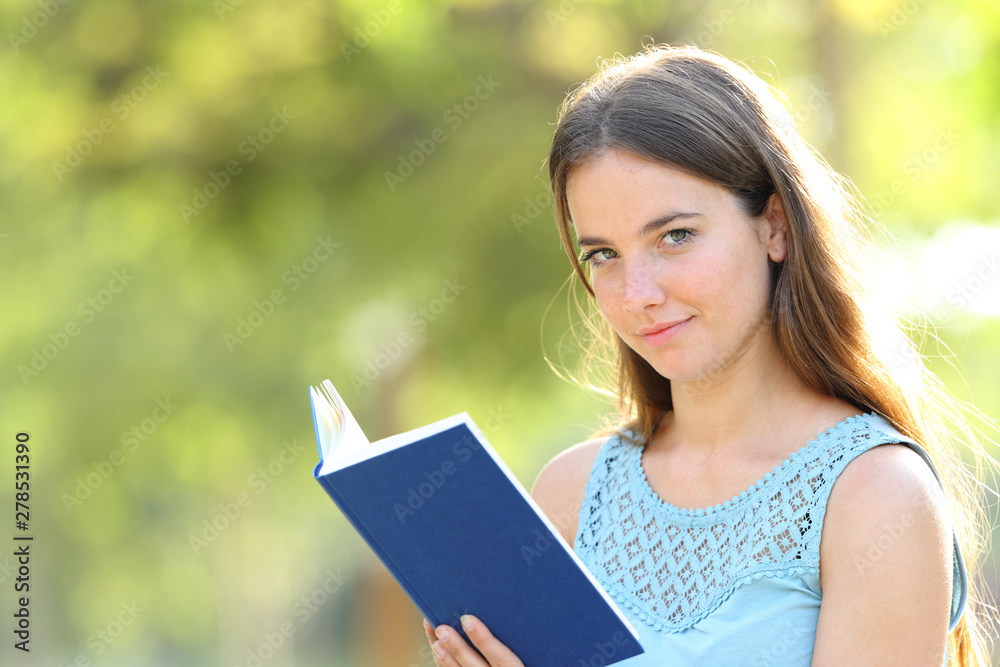 Serious woman looks at camera holding a book Serious woman looks at camera holding a book