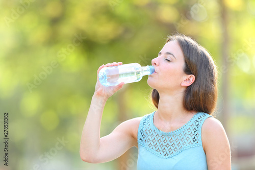 Casual woman drinking bottled water in a park