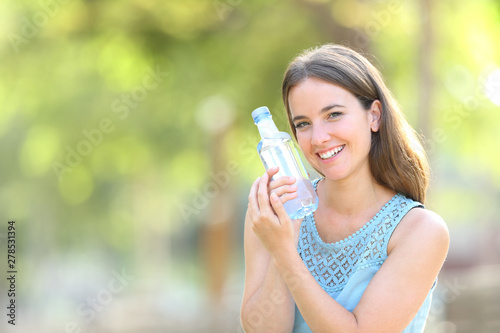 Woman loving a plastic water bottle on green