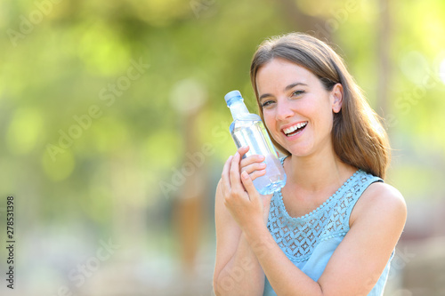 Woman showing a plastic water bottle on green