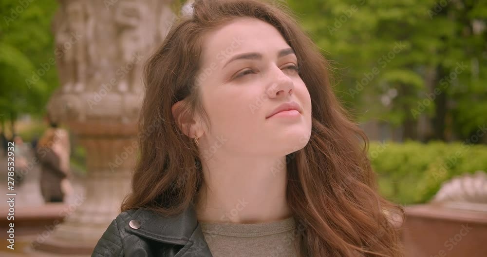 Close-up shot of caucasian brunette model opens umbrella predicting the rain in the green rainy park. Close-up shot of caucasian brunette model opens umbrella predicting the rain in the green rainy park.