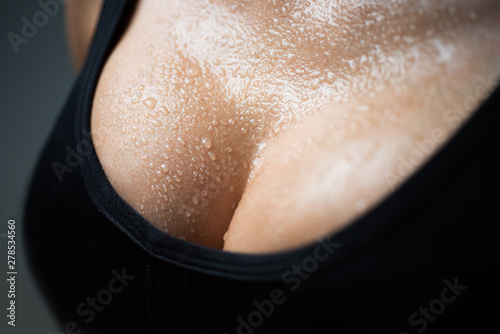 Closeup portrait of a female sexy big wet breast. Young beautiful girl shows her gorgeous breasts. Woman body. photo