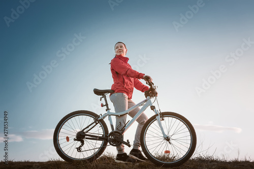 young woman with mountain bike at the sunset.