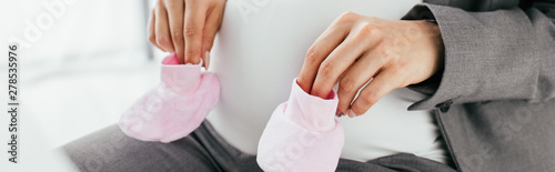 panoramic view of pregnant woman holding pink slippers