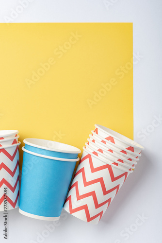Multicolored eco paper party cups on yellow background