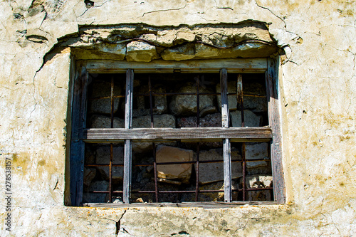 Window in the wall of an abandoned house. Old house. The ruins of the house. Window with bars.