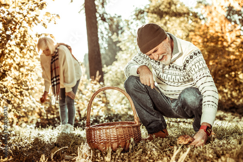 Happy senior couple gathering mushrooms in the forest together.