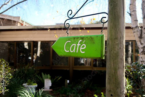 Arrow shaped Cafe sign on post, soft focus background