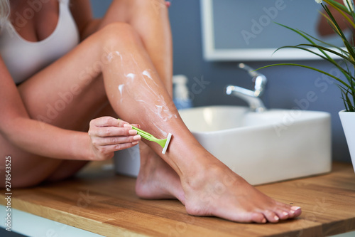 Beautiful woman shaving legs in the bathroom photo