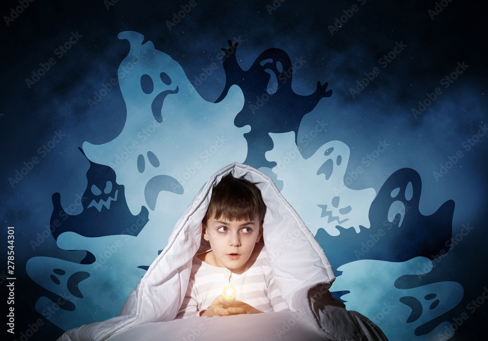 Surprised boy hiding under blanket