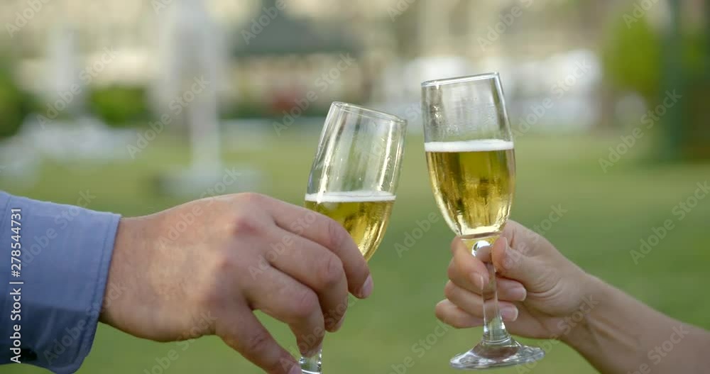 man and woman are clinking glasses with champagne outdoors in garden, close-up view man and woman are clinking glasses with champagne outdoors in garden, close-up view