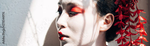 Obraz na płótnie portrait of beautiful geisha with red and white makeup in sunlight with shadows,