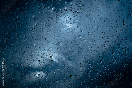 Fresh water drops after raining on blue glass window background in car.