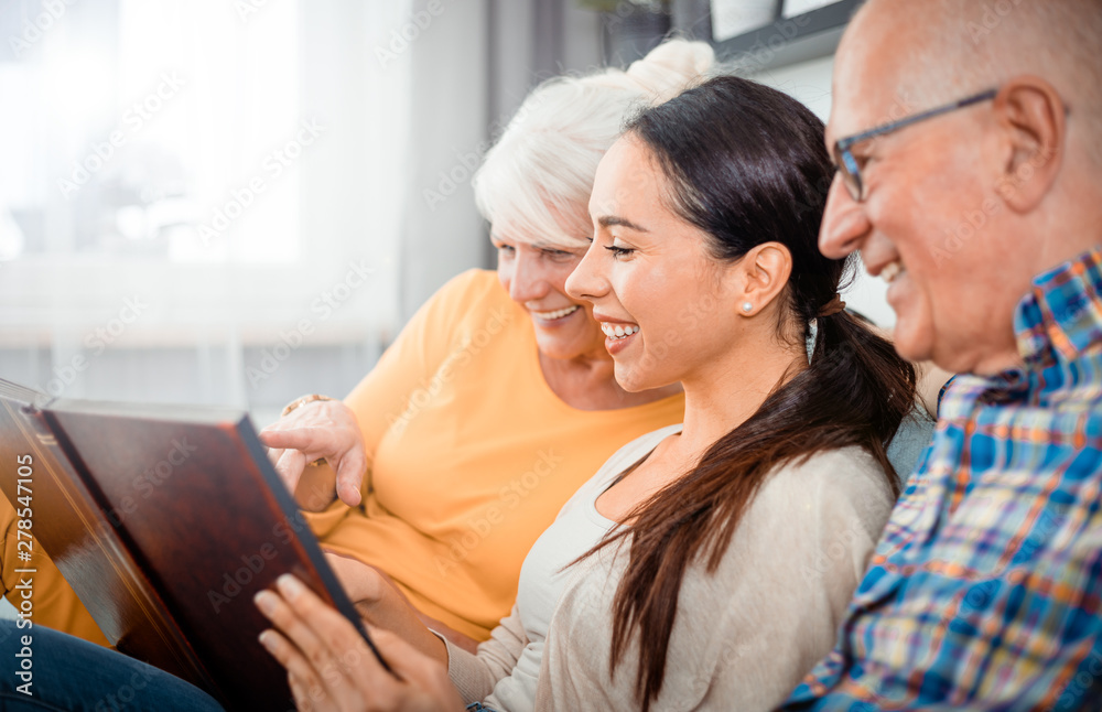 Happy senior parents with their daughter looking at photos in family album Happy senior parents with their daughter looking at photos in family album