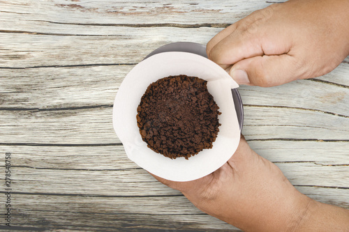Hand drip coffee with filter on wood background