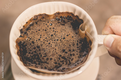 cup of drip coffee with paper filter tool