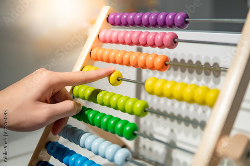 Male hand calculating with beads on wooden rainbow abacus for number calculation. Mathematics learning concept photo