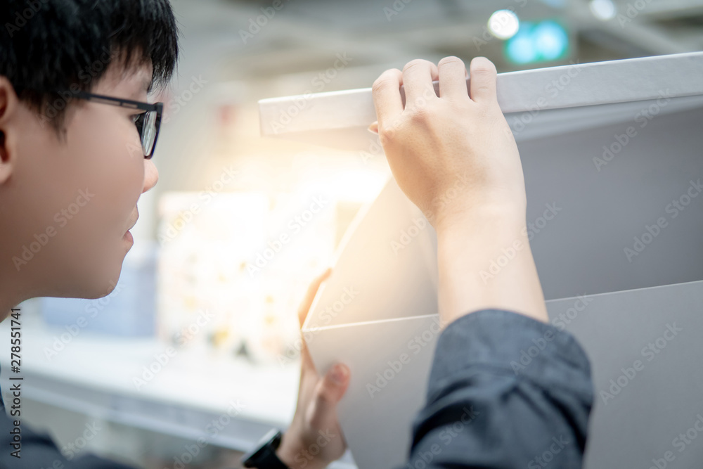 Asian man opening empty white paper box in grocery store. Packaging design for home decoration. Unboxing concept