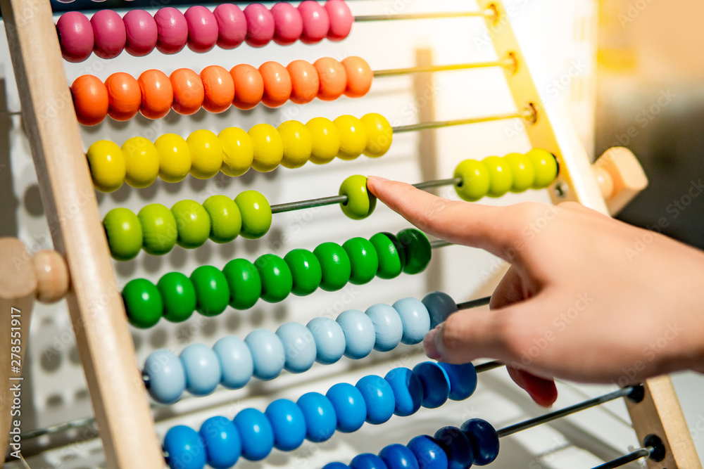 Male hand calculating with beads on wooden rainbow abacus for number calculation. Mathematics learning concept Male hand calculating with beads on wooden rainbow abacus for number calculation. Mathematics learning concept