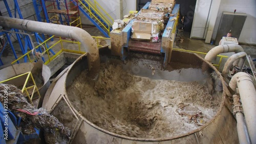 liquid cellulose mixes in tank by wastepaper blocks in shop photo