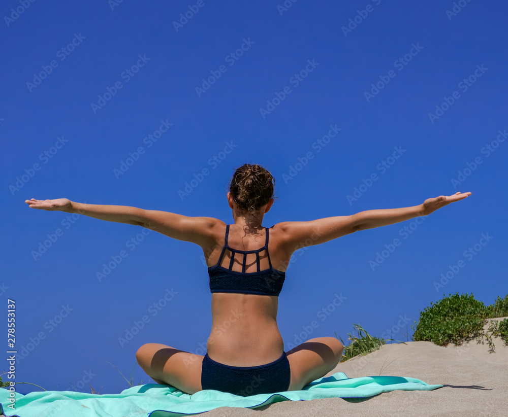 Slim and athletic girl in a black bikini doing yoga pose, calisthenics, fitness  training, workout on a beach with blue sky, fitness-wellness foto de Stock  | Adobe Stock