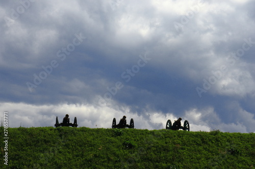 View of the hill with cannons near the old fortress. Dark cloudy sky.